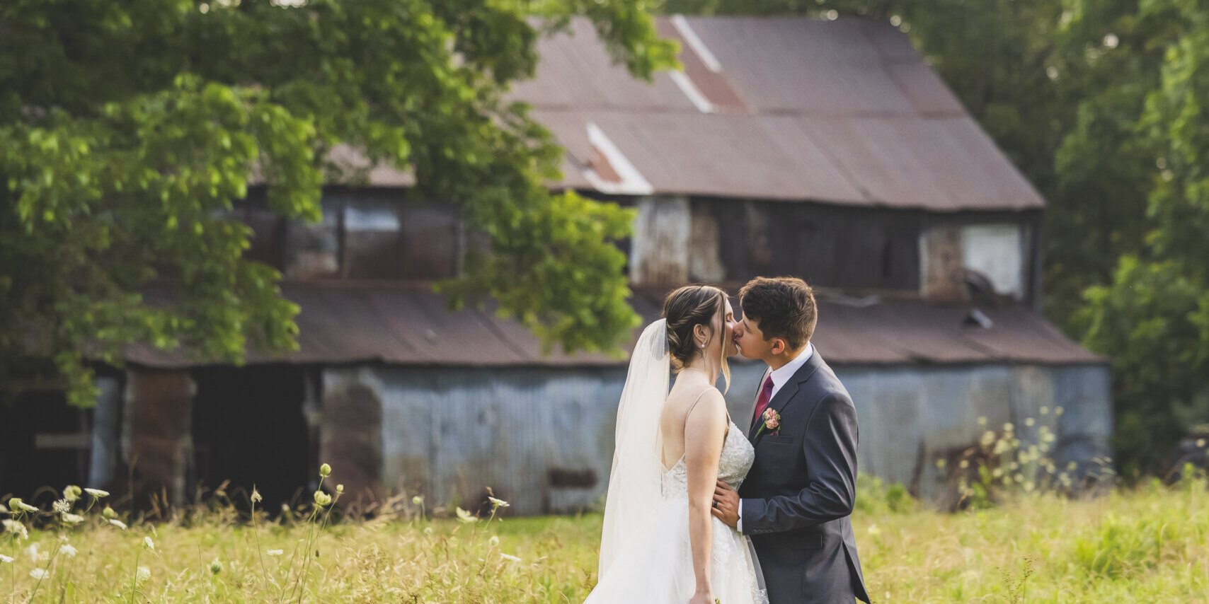 Bride and groom kissing in a field
