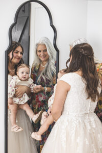 Bride, her mom, and the flower girl looking into a mirror