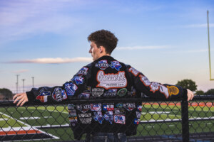 Boy in letterman leaning on the fence