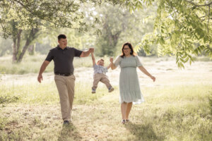 Mom and dad walking in a field picking up their son